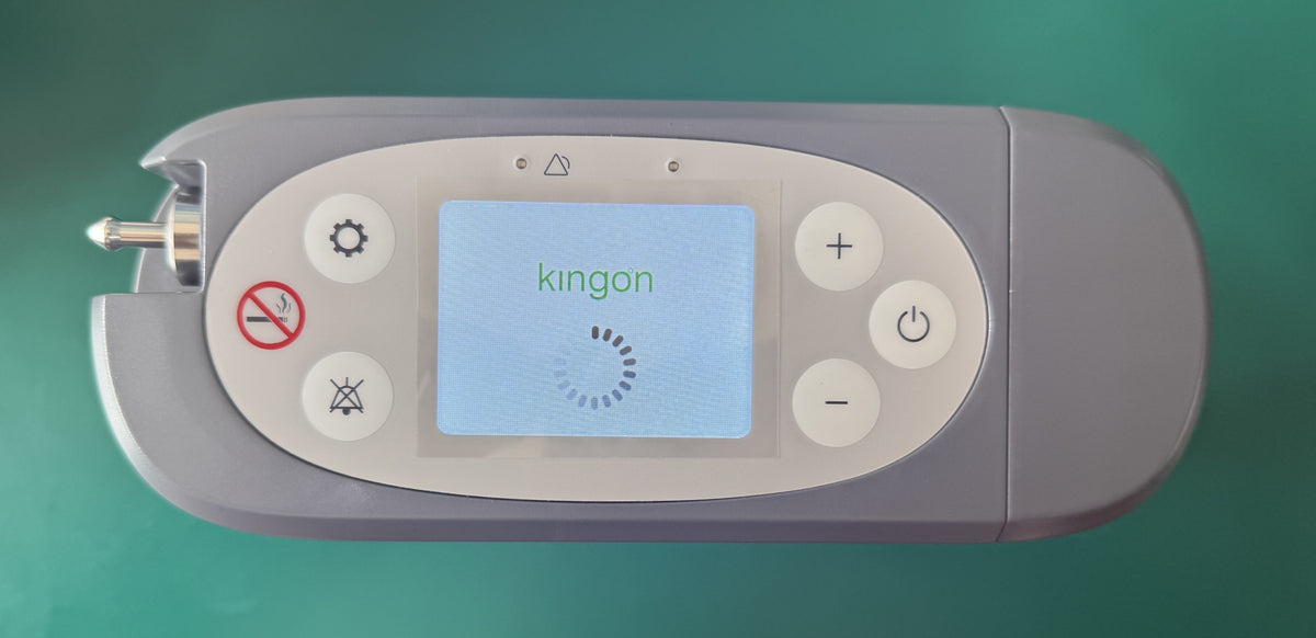Top-down photo of the Kingon P2-E control panel with the Kingon start-up screen loading, oxygen outlet port on the left